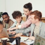 A group of professionals engaged in a collaborative office meeting, discussing ideas with laptops.